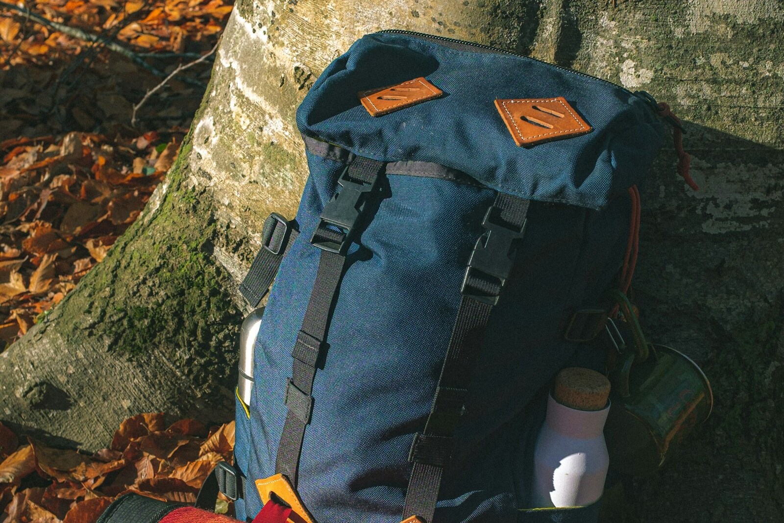A packed backpack with a bedroll and water bottle