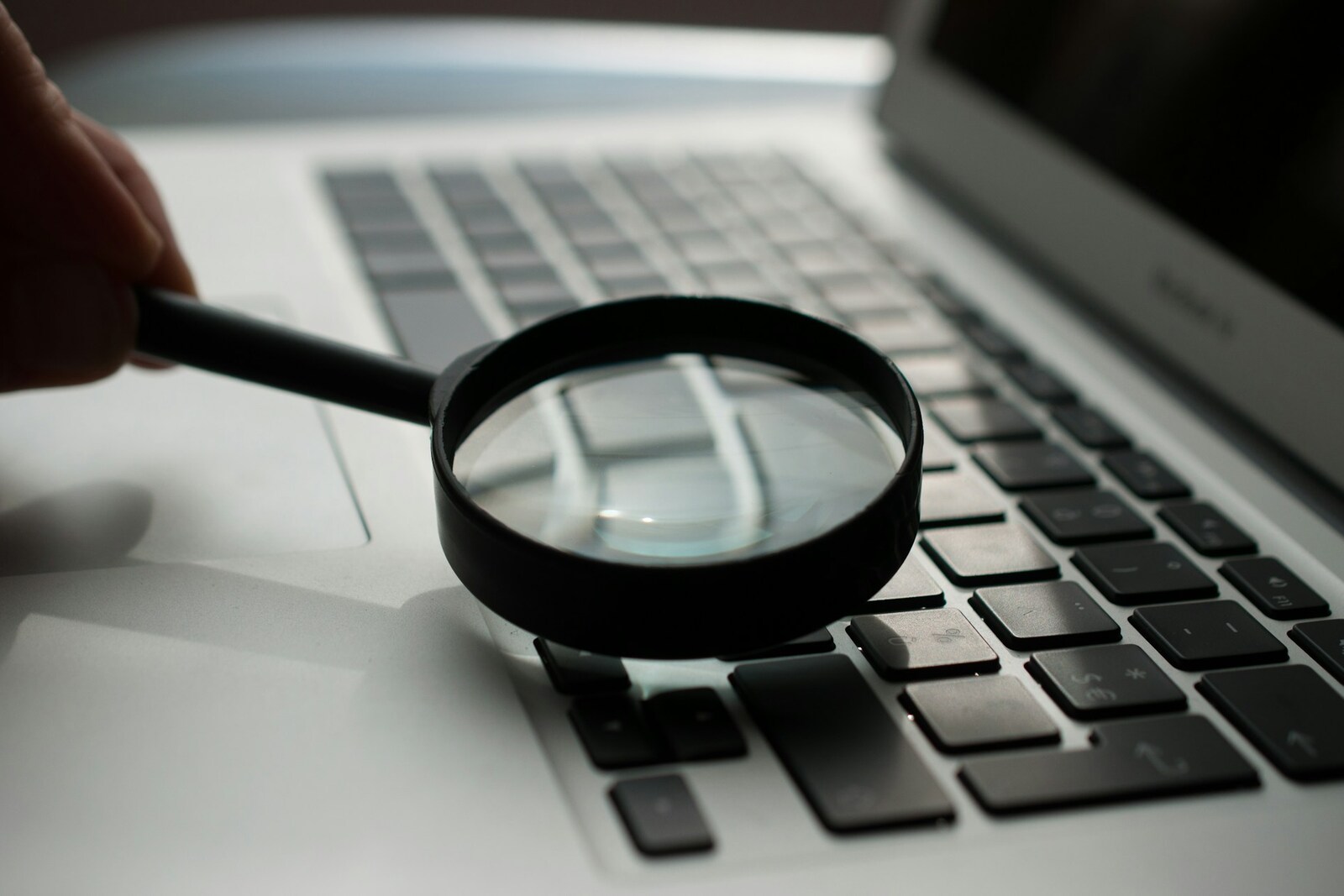 A magnifying glass held over a laptop keyboard