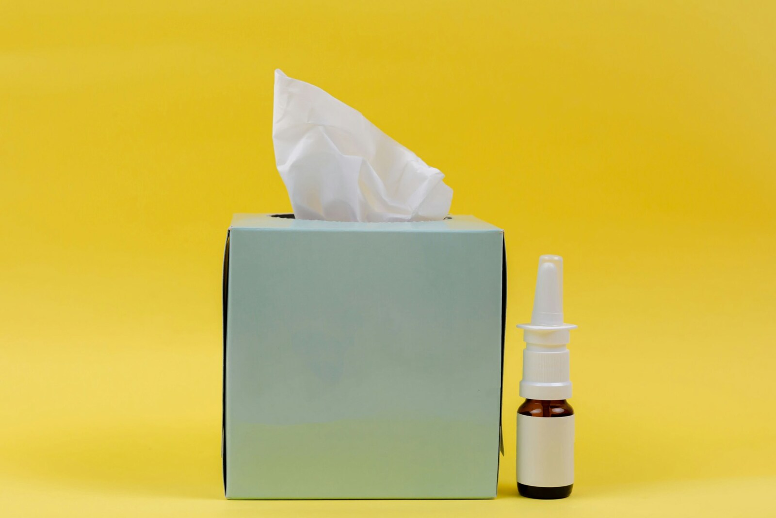 A tissue box and nasal spray bottle