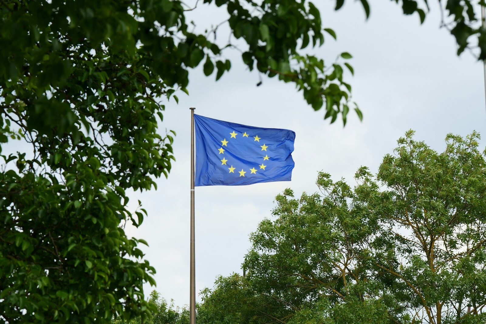 The European Union flag waving against a cloudy sky