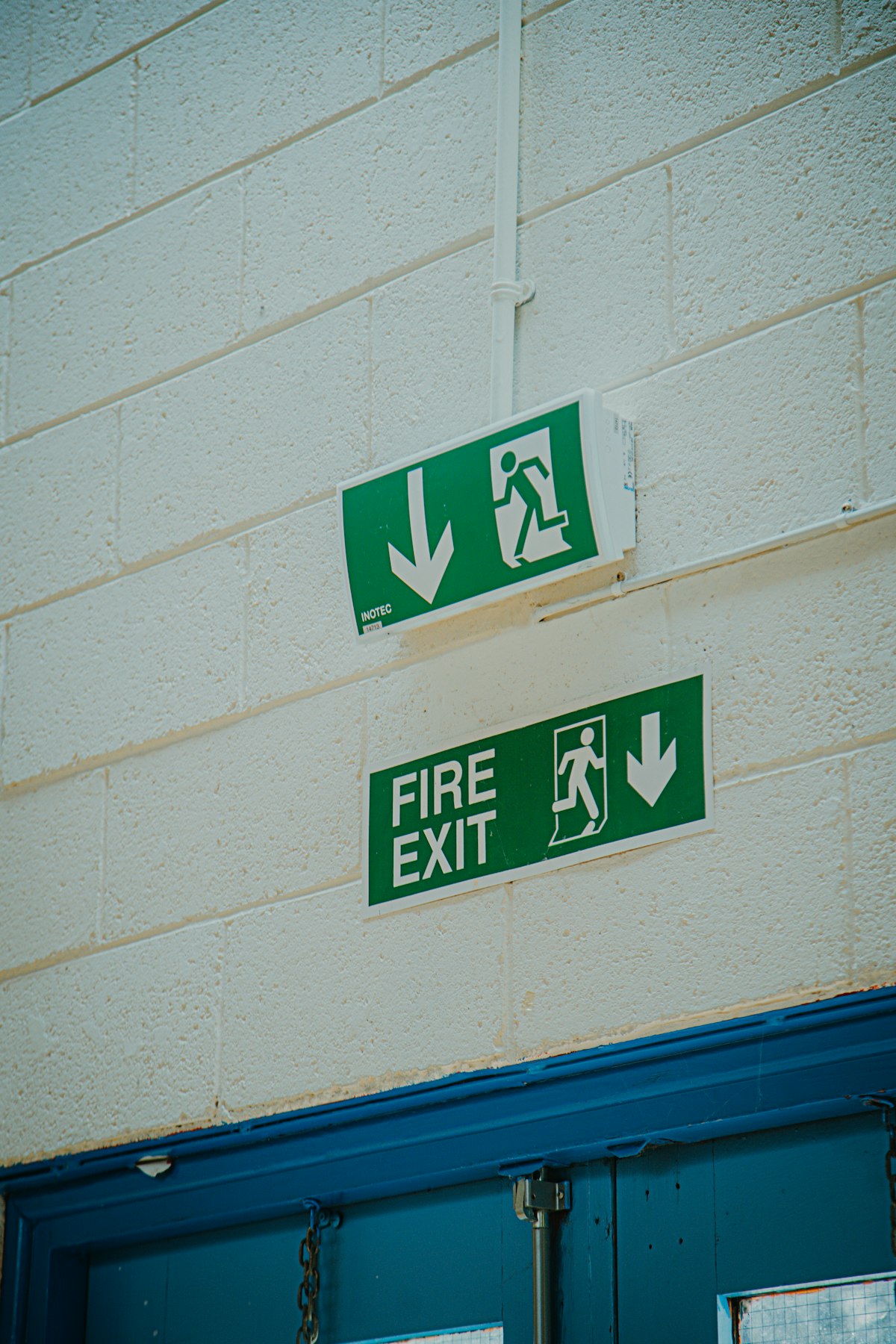 A green fire exit sign mounted on a building wall